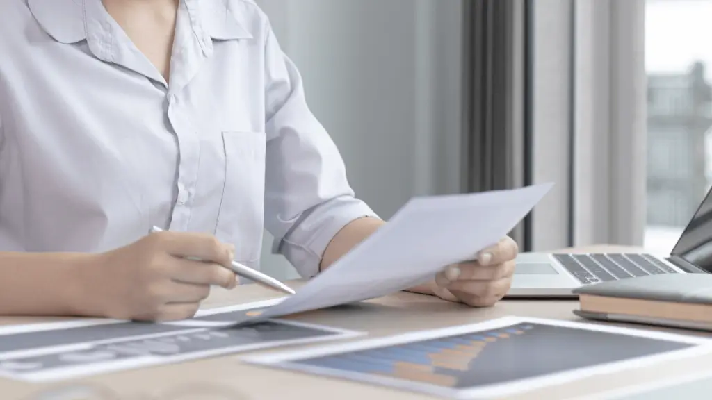 Ženska sedi za mizo in preglejuje rezultate.